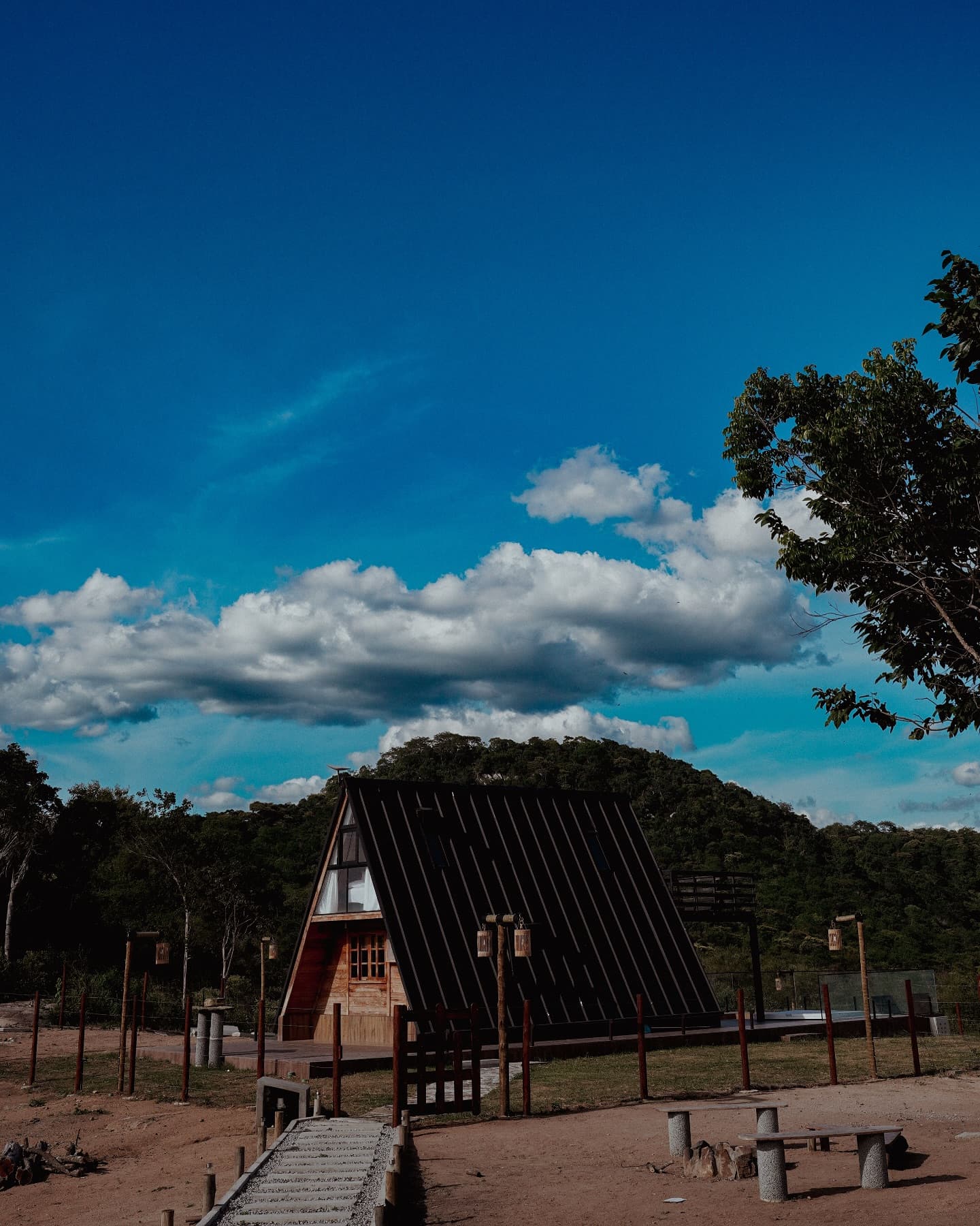 Chalé do Vale visto ao longe, cercado pela serra de Pedra sob um céu dramático